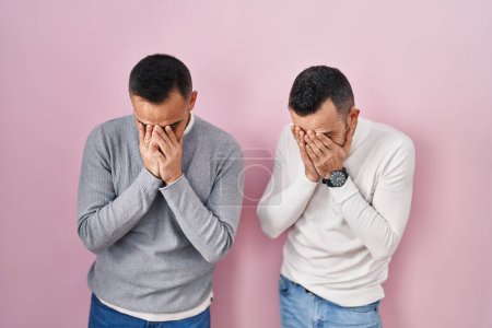 Photo for Homosexual couple standing over pink background with sad expression covering face with hands while crying. depression concept. - Royalty Free Image