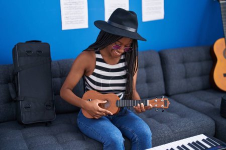 Téléchargez les photos : Femme musicienne afro-américaine jouant de l'ukulélé au studio de musique - en image libre de droit