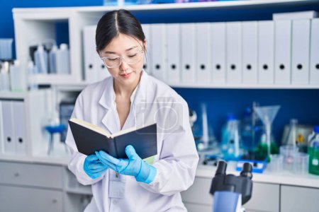 Photo for Chinese woman scientist reading book at laboratory - Royalty Free Image