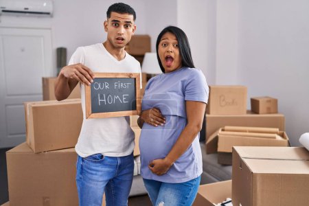 Photo for Young hispanic couple expecting a baby moving to a new home in shock face, looking skeptical and sarcastic, surprised with open mouth - Royalty Free Image