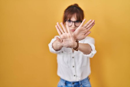 Photo for Young beautiful woman wearing casual shirt over yellow background rejection expression crossing arms and palms doing negative sign, angry face - Royalty Free Image