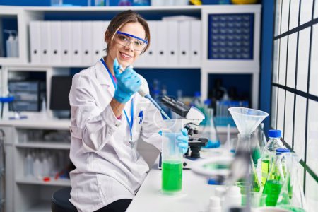 Photo for Young beautiful hispanic woman scientist smiling confident pouring liquid on test tube at laboratory - Royalty Free Image