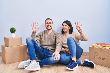 Photo for Young couple moving to a new home showing and pointing up with fingers number nine while smiling confident and happy. - Royalty Free Image