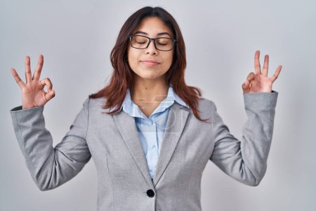 Photo for Hispanic young business woman wearing glasses relax and smiling with eyes closed doing meditation gesture with fingers. yoga concept. - Royalty Free Image