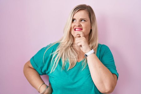 Foto de Caucasian plus size woman standing over pink background thinking worried about a question, concerned and nervous with hand on chin - Imagen libre de derechos