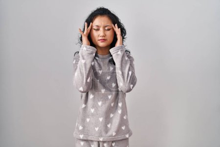 Photo for Young asian woman wearing pajama with hand on head for pain in head because stress. suffering migraine. - Royalty Free Image
