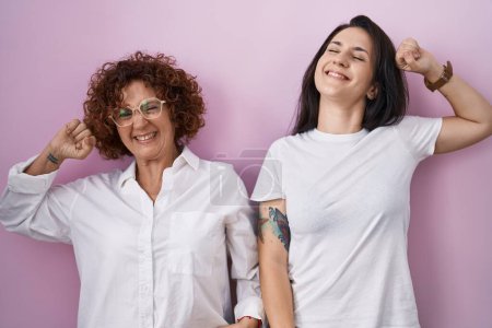 Photo for Hispanic mother and daughter wearing casual white t shirt over pink background stretching back, tired and relaxed, sleepy and yawning for early morning - Royalty Free Image