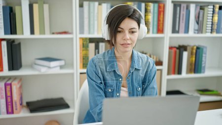 Téléchargez les photos : Jeune étudiante caucasienne utilisant un casque d'ordinateur en classe universitaire - en image libre de droit