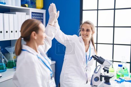 Photo for Two women scientists high five with hands raised up at laboratory - Royalty Free Image