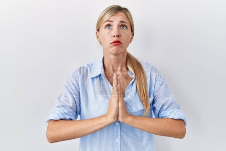 Photo for Beautiful blonde woman standing over white background begging and praying with hands together with hope expression on face very emotional and worried. begging. - Royalty Free Image