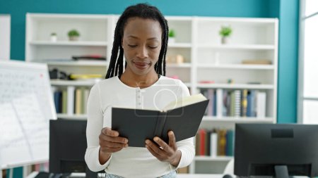 Téléchargez les photos : African american woman student reading book standing at university classroom - en image libre de droit