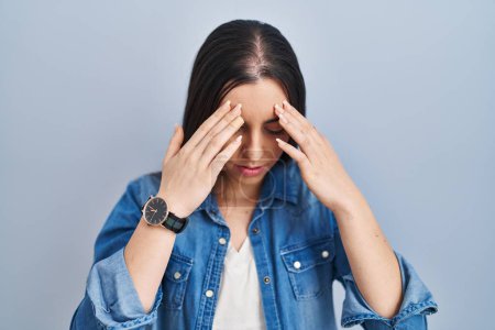 Photo for Hispanic woman standing over blue background rubbing eyes for fatigue and headache, sleepy and tired expression. vision problem - Royalty Free Image