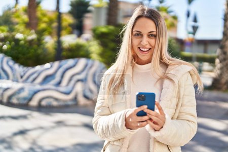 Photo for Young woman smiling confident using smartphone at park - Royalty Free Image