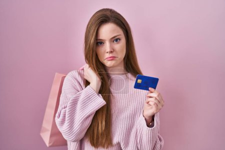 Photo for Young caucasian woman holding shopping bag and credit card depressed and worry for distress, crying angry and afraid. sad expression. - Royalty Free Image