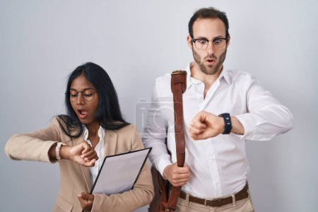 Téléchargez les photos : Couple d'affaires Interracial portant des lunettes regardant l'heure de la montre inquiet, peur de se faire tard - en image libre de droit
