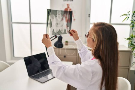 Foto de Joven mujer rubia médico usando portátil celebración de rayos X en la clínica - Imagen libre de derechos