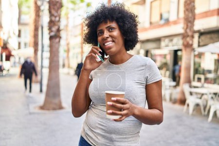 Photo for African american woman talking on smartphone drinking coffee at street - Royalty Free Image