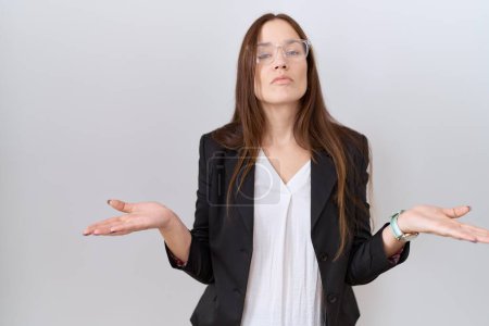 Photo for Beautiful brunette woman wearing business jacket and glasses clueless and confused with open arms, no idea concept. - Royalty Free Image