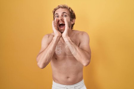 Téléchargez les photos : Blanc homme debout torse nu portant écran solaire criant en colère à haute voix avec les mains sur la bouche - en image libre de droit