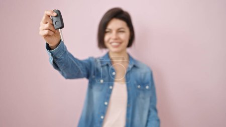 Téléchargez les photos : Jeune femme caucasienne souriante confiante tenant la clé de la nouvelle voiture sur fond rose isolé - en image libre de droit