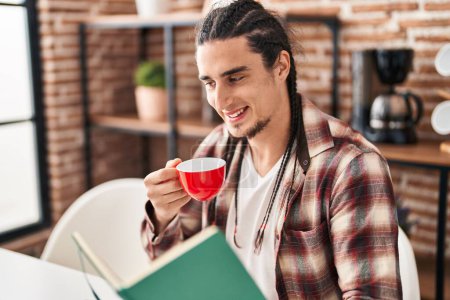 Photo for Young man reading book drinking coffee at home - Royalty Free Image