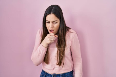 Photo for Young brunette woman standing over pink background feeling unwell and coughing as symptom for cold or bronchitis. health care concept. - Royalty Free Image