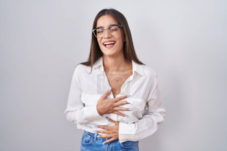 Photo for Young brunette woman wearing glasses smiling and laughing hard out loud because funny crazy joke with hands on body. - Royalty Free Image