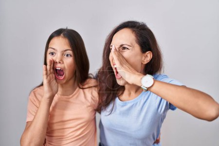Photo for Young mother and daughter standing over white background shouting and screaming loud to side with hand on mouth. communication concept. - Royalty Free Image