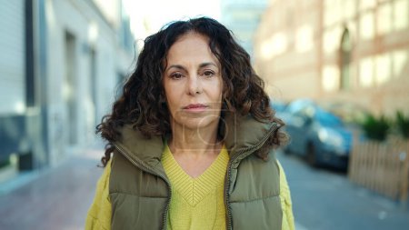 Téléchargez les photos : Middle age hispanic woman standing with relaxed expression at street - en image libre de droit