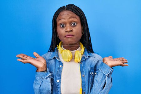 Photo for African woman with braids standing over blue background shouting and screaming loud to side with hand on mouth. communication concept. - Royalty Free Image