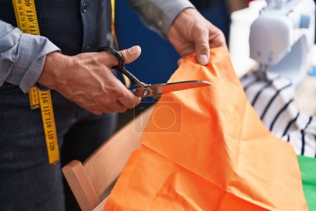 Téléchargez les photos : Middle age grey-haired man tailor cutting cloth at clothing factory - en image libre de droit