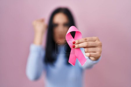 Photo for Hispanic woman holding pink cancer ribbon annoyed and frustrated shouting with anger, yelling crazy with anger and hand raised - Royalty Free Image