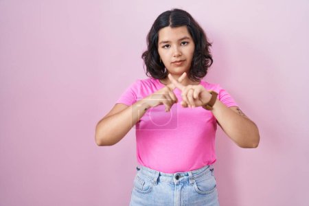 Téléchargez les photos : Jeune femme hispanique debout sur fond rose expression de rejet croisant les doigts faisant signe négatif - en image libre de droit