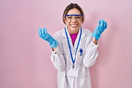 Photo for Hispanic woman wearing scientist uniform celebrating mad and crazy for success with arms raised and closed eyes screaming excited. winner concept - Royalty Free Image
