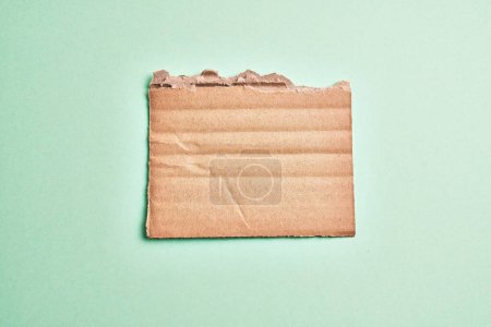Photo for One ripped piece of cardboard material over isolated green background - Royalty Free Image