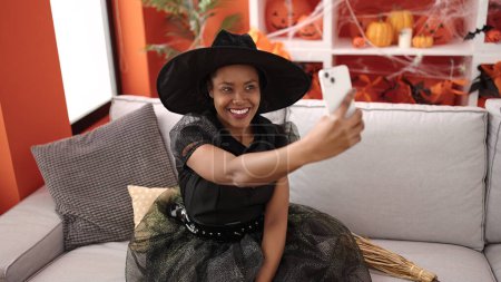 Foto de African american woman wearing witch costume make selfie by smartphone at home - Imagen libre de derechos