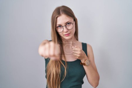 Téléchargez les photos : Jeune femme caucasienne debout sur fond blanc coups de poing poing pour se battre, agressif et en colère attaque, menace et violence - en image libre de droit