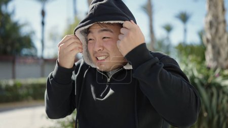 Téléchargez les photos : Jeune homme chinois portant la tête avec capuche au parc - en image libre de droit