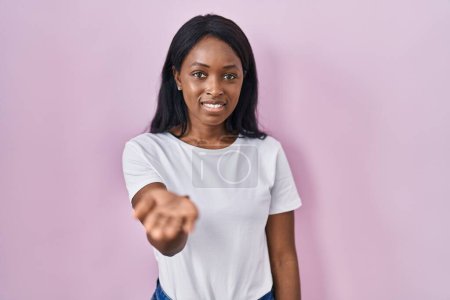 Téléchargez les photos : Africaine jeune femme portant casual t-shirt blanc souriant joyeuse offrant main de paume donnant assistance et acceptation. - en image libre de droit