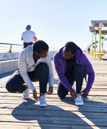 Photo for Man and woman couple wearing sportswear tying shoes at seaside - Royalty Free Image