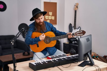 Téléchargez les photos : Young redhead man musician singing song playing classical guitar at music studio - en image libre de droit
