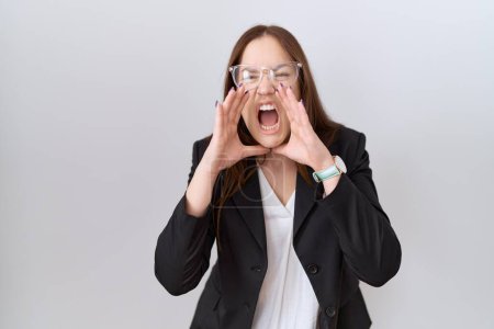 Photo for Beautiful brunette woman wearing business jacket and glasses shouting angry out loud with hands over mouth - Royalty Free Image