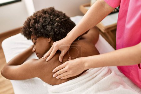 Téléchargez les photos : Jeune femme afro-américaine ayant massage du dos au centre de beauté - en image libre de droit
