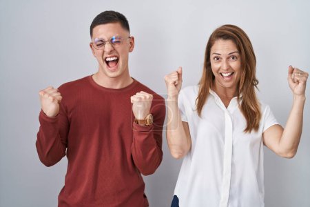 Photo for Mother and son standing together over isolated background celebrating surprised and amazed for success with arms raised and eyes closed. winner concept. - Royalty Free Image