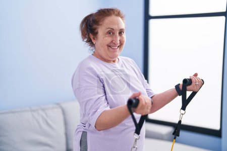 Photo for Senior woman smiling confident using elastic band training at home - Royalty Free Image