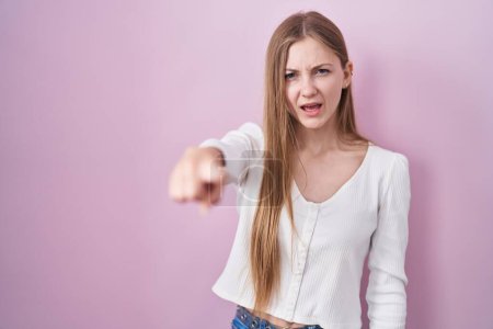 Téléchargez les photos : Young caucasian woman standing over pink background pointing displeased and frustrated to the camera, angry and furious with you - en image libre de droit
