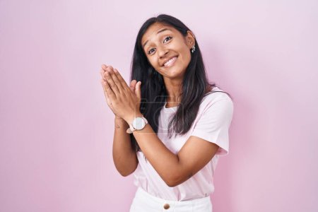 Foto de Joven mujer hispana de pie sobre fondo rosa aplaudiendo y aplaudiendo felices y alegres, sonriendo orgullosas manos juntas - Imagen libre de derechos