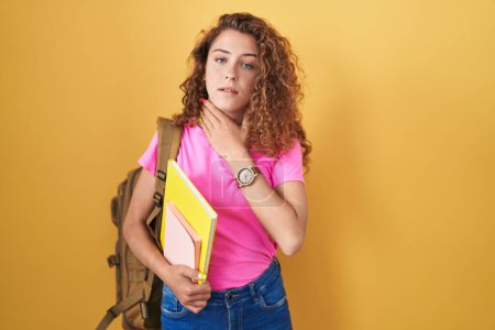 Photo for Young caucasian woman wearing student backpack and holding books touching painful neck, sore throat for flu, clod and infection - Royalty Free Image