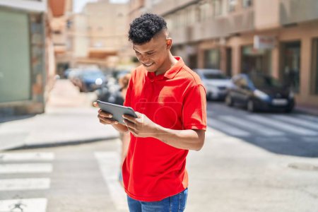 Téléchargez les photos : Young latin man smiling confident using touchpad at street - en image libre de droit