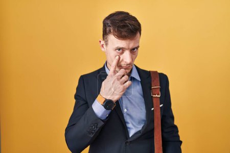 Photo for Caucasian business man over yellow background pointing to the eye watching you gesture, suspicious expression - Royalty Free Image